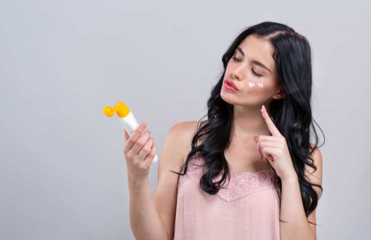 donna che guarda crema solare